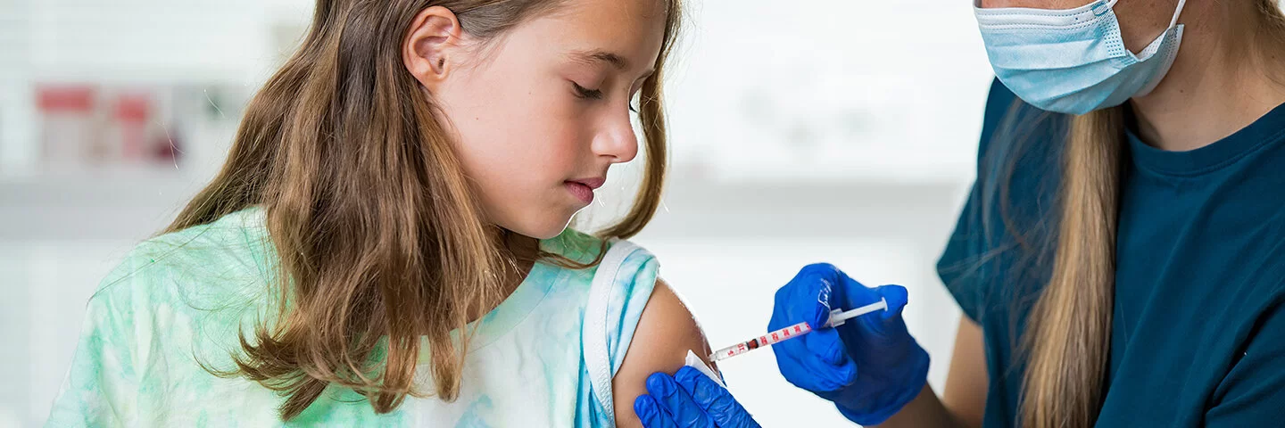 Etwa 11-jähriges Mädchen erhält eine Impfung in den linken Oberarm.