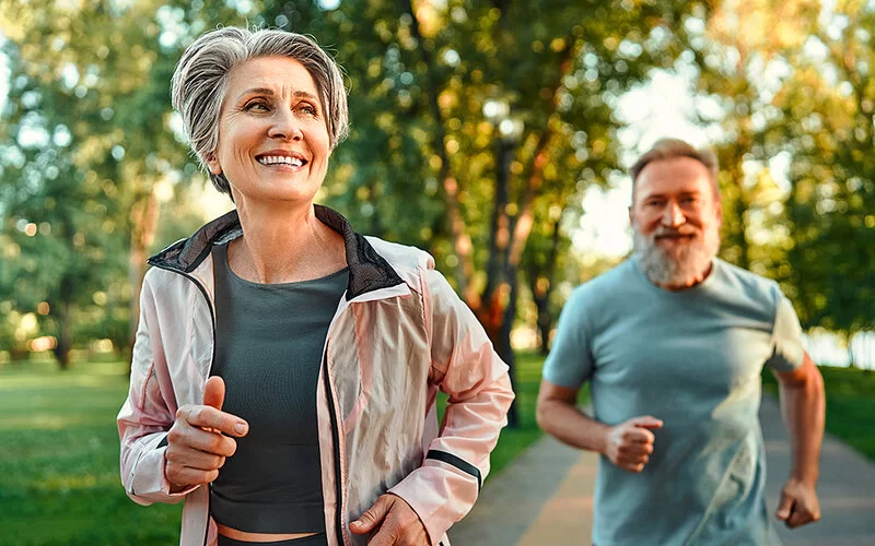 Ein älteres Paar beim Joggen in einem sommerlichen Park.