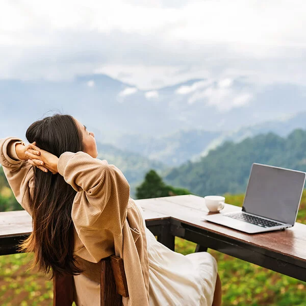 Frau macht Workation und genießt ihren Ausblick auf die Berge.