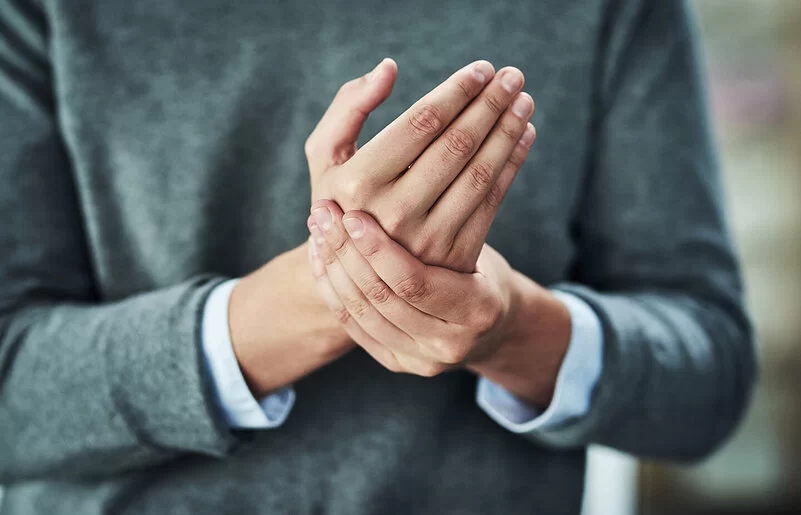 Eine Frau hält mit ihrer linken Hand die rechte Hand fest.