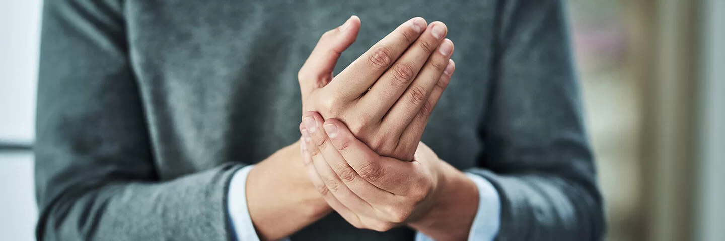 Eine Frau hält mit ihrer linken Hand die rechte Hand fest.