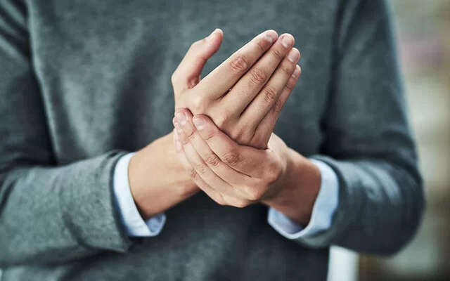 Eine Frau hält mit ihrer linken Hand die rechte Hand fest.