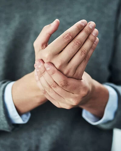 Eine Frau hält mit ihrer linken Hand die rechte Hand fest.