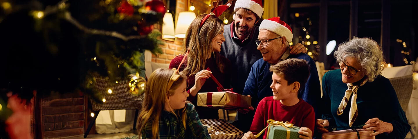 Glückliche Großfamilie, die Geschenke am Weihnachtsbaum zu Hause öffnet.