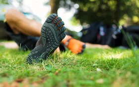 Eine Person liegt mit Barfußschuhen im Gras.