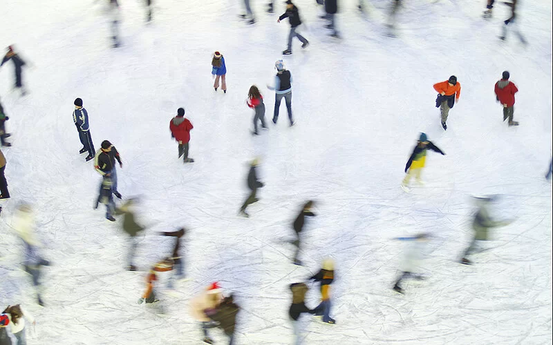 Zahlreiche Menschen gleiten über eine Eisfläche.