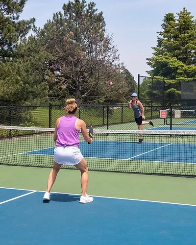 Jeweils zwei Spielerinnen stehen sich auf einem Pickleballfeld bei einem Doppel gegenüber.