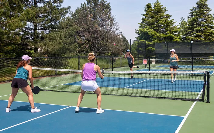 Jeweils zwei Spielerinnen stehen sich auf einem Pickleballfeld bei einem Doppel gegenüber.