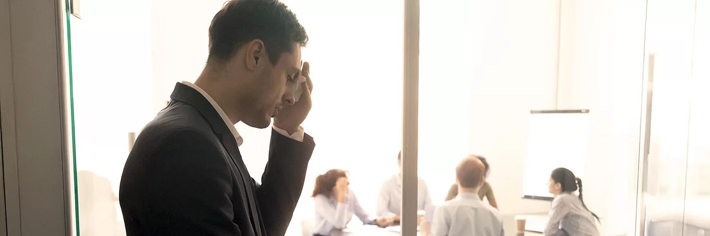 Ein Mann ist nervös vor einem Vortrag im Büro und tupft sich den Schweiß von der Stirn.