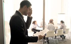 Ein Mann ist nervös vor einem Vortrag im Büro und tupft sich den Schweiß von der Stirn.