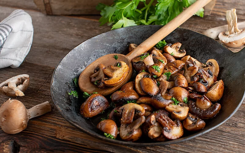 Nahaufnahme einer gusseisernen Pfanne mit Champignons.