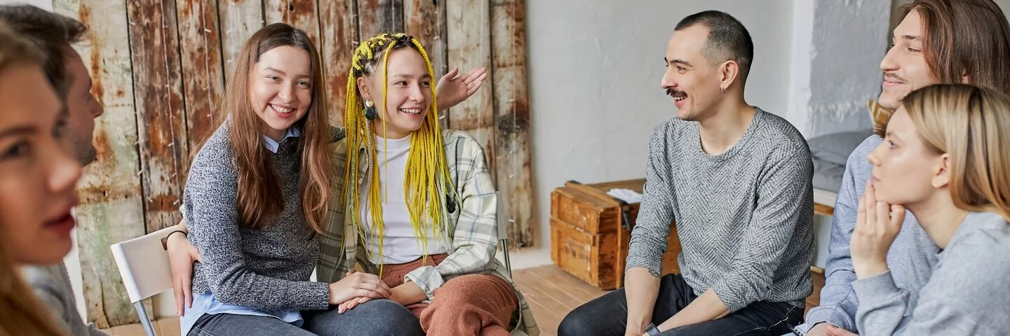 Gruppe von jungen Leuten sitzt zusammen und unterhält sich.