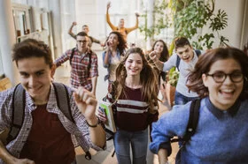 Eine Gruppe glücklicher Schüler läuft auf die Kamera zu.