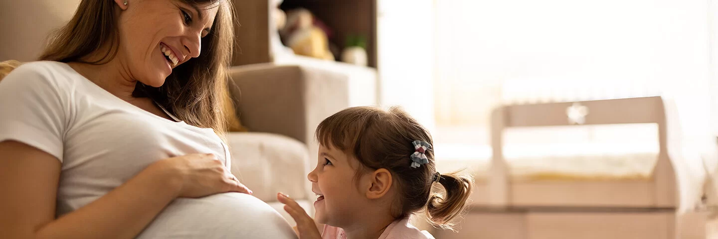 Junge Mutter freut sich mit Tochter auf ein weiteres Baby