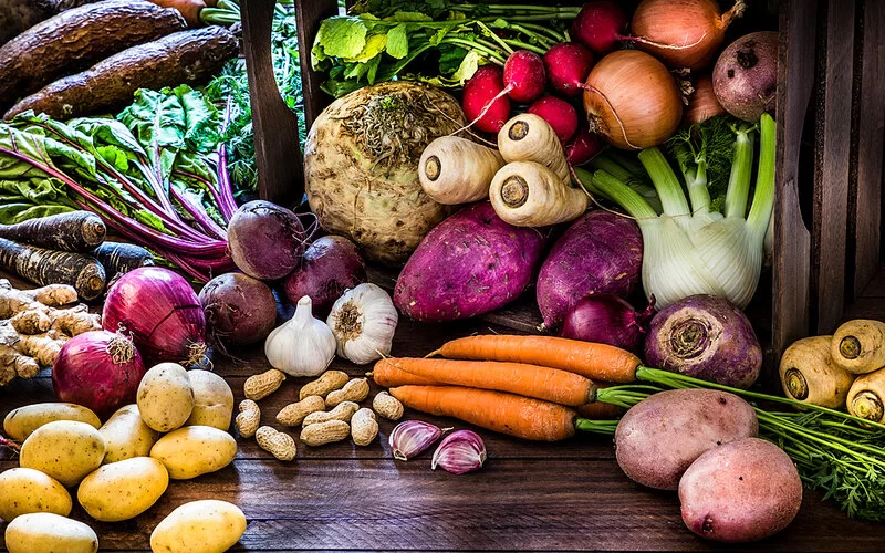 Verschiedene Gemüsesorten liegen auf einem Holztisch beieinander.