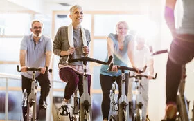 Ein Gruppe sportlicher Personen macht Spinning in einem Fitnessstudio.