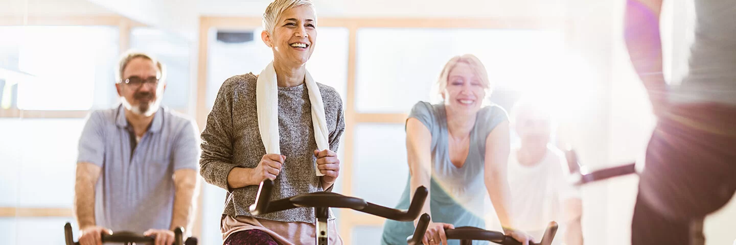 Ein Gruppe sportlicher Personen macht Spinning in einem Fitnessstudio.