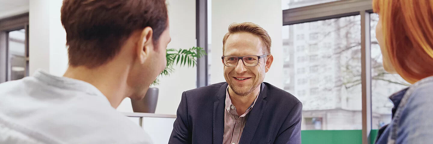 Ein Mann im Gespräch mit einem jüngeren Paar. Bei Behandlungsfehlern unterstützt die AOK Patienten.