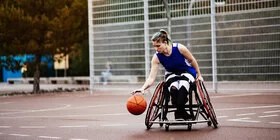 Eine Frau im Rollstuhl spielt Basketball.