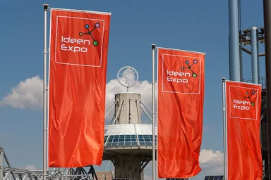 Drei rote Flaggen mit dem Logo der Ideenexpo wehen vor dem Eingang der Hannover Messe.