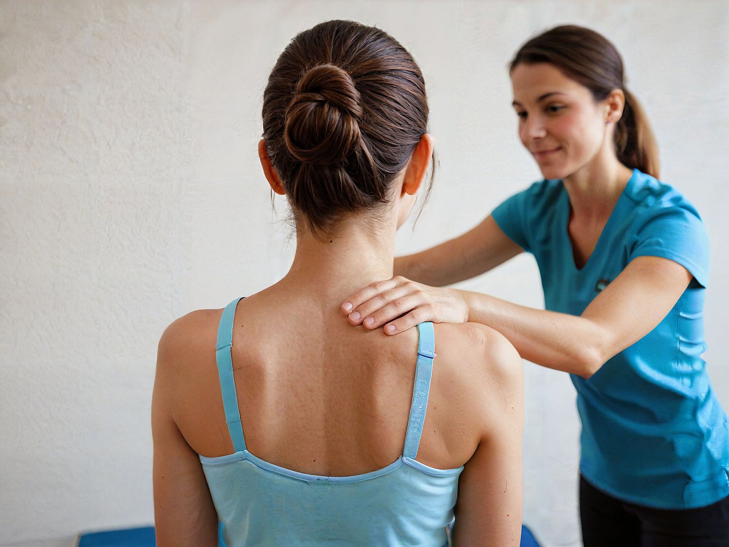 Eine Physiotherapeutin berührt ihre Patientin an der Schulter.