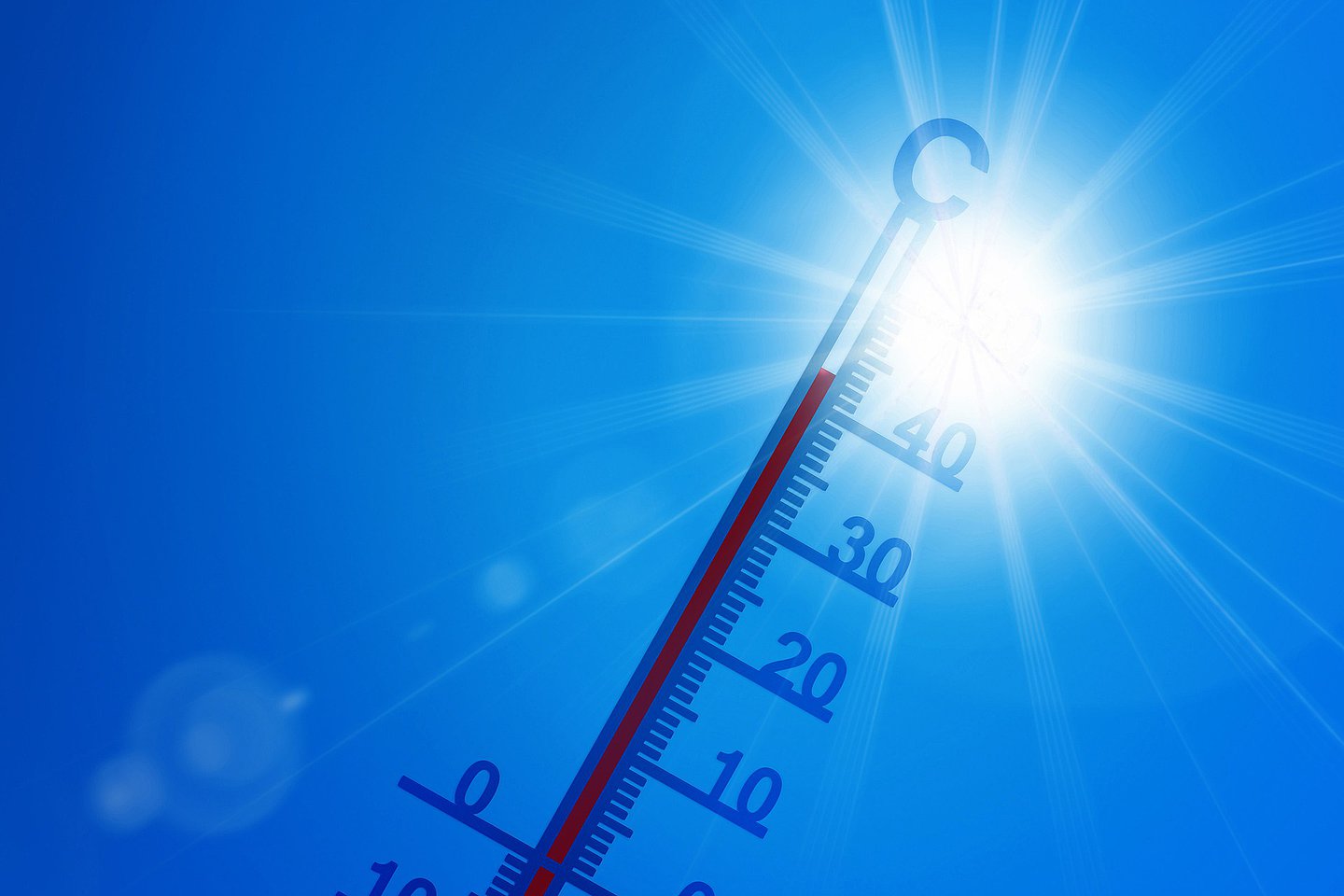 Symbolbild für Hitze: Ein Thermometer vor der Sonne am wolkenlosen Himmel