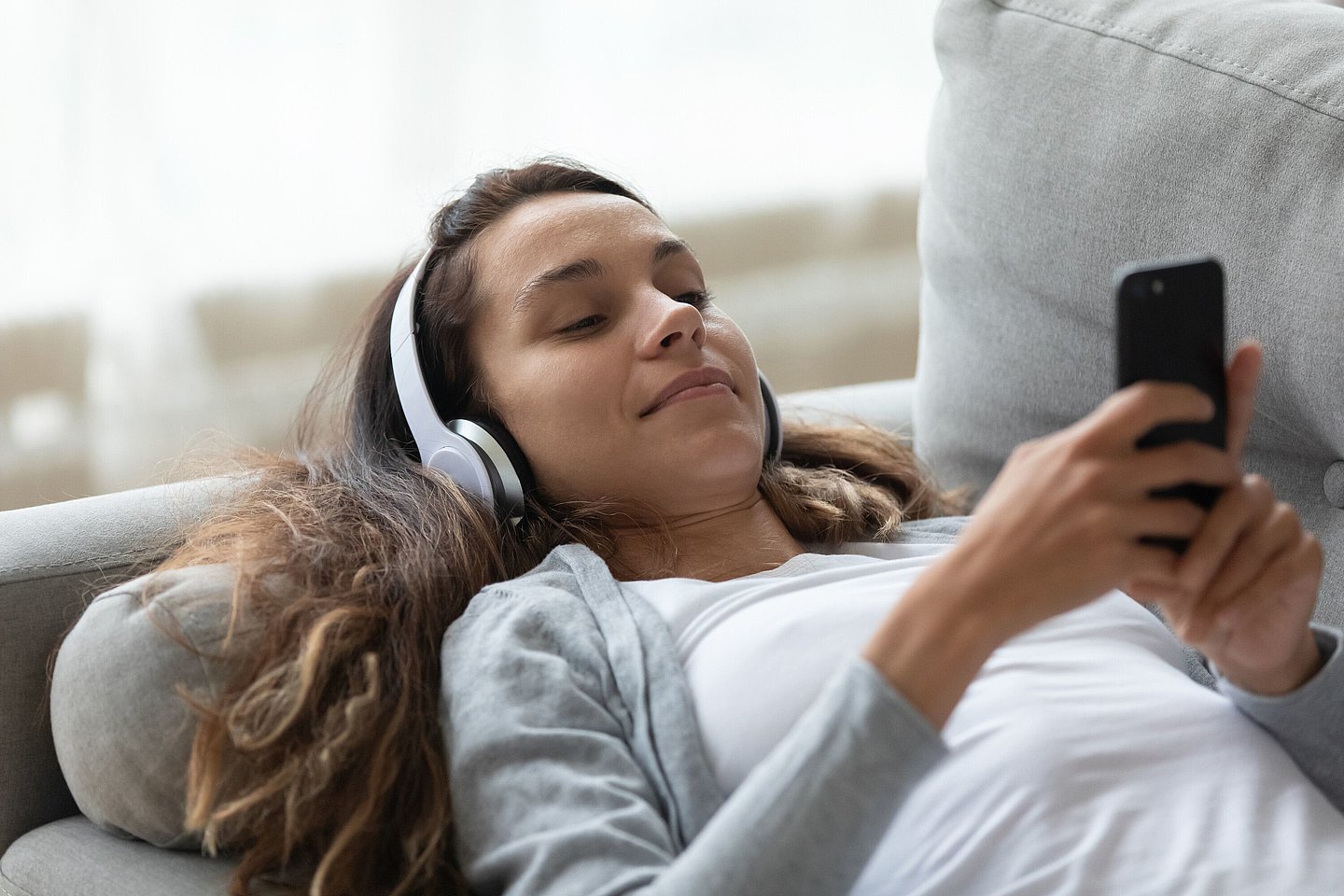 Eine junge Frau chillt auf der Couch.