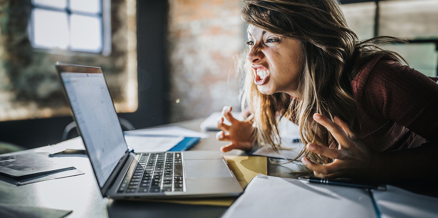 Foto: Eine Frau hat einen Wutanfall vor einem Laptop.