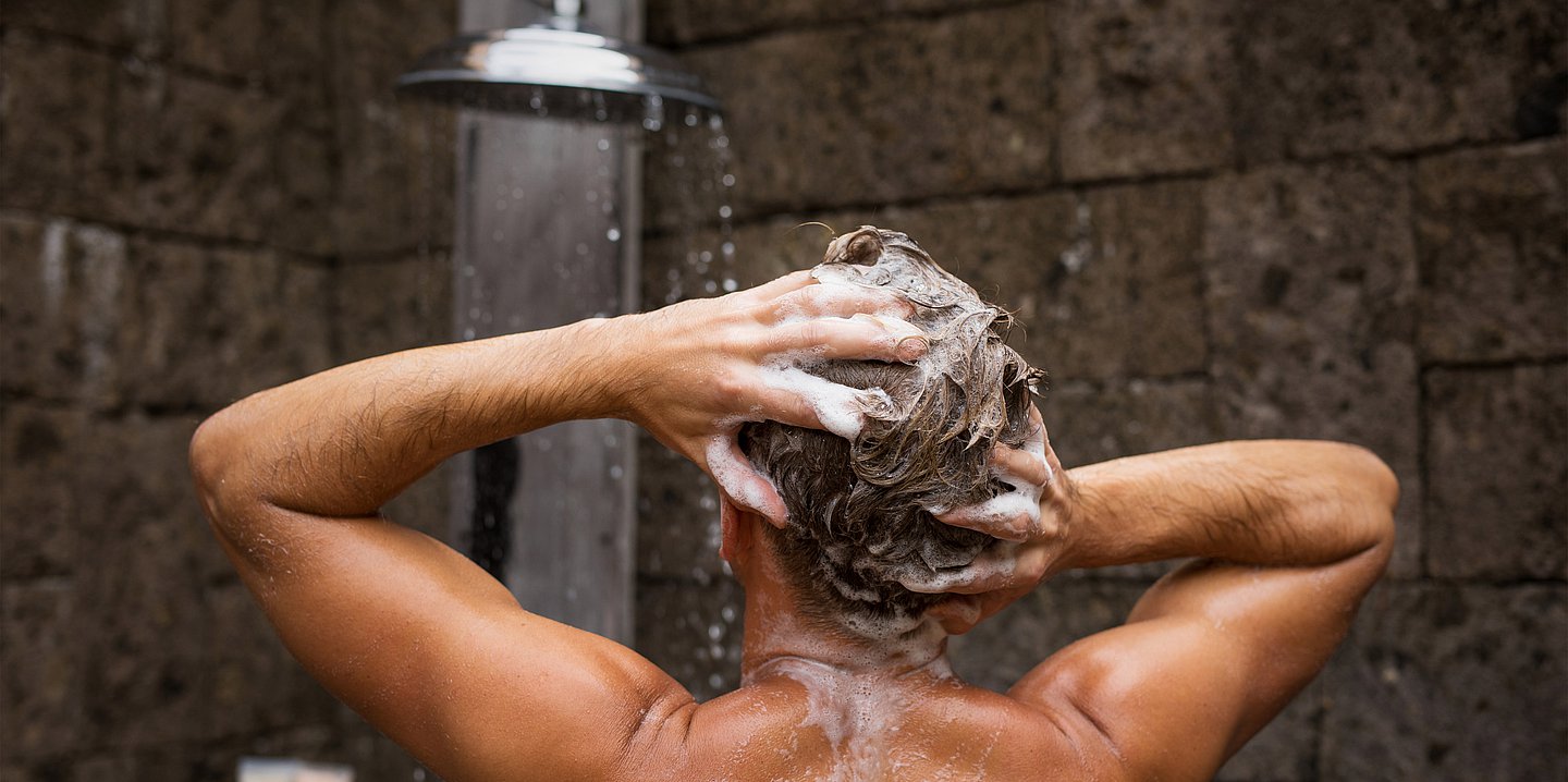 Foto: Ein Mann steht unter der Dusche und wäscht sich gerade die Haare.
