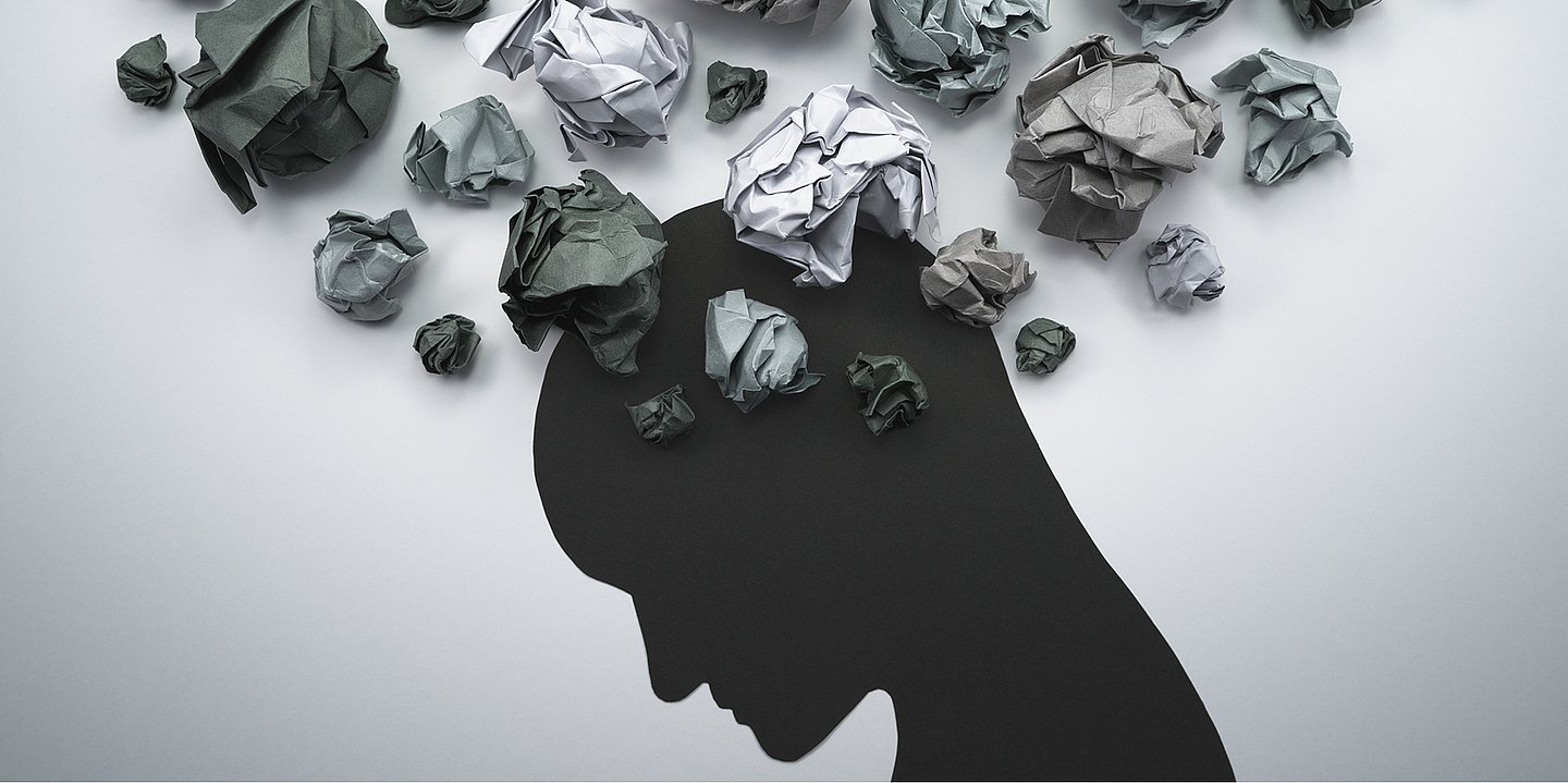 Foto: Illustration eines Kopfes über dem sich viele zerknüllte Papierzettel ballen.