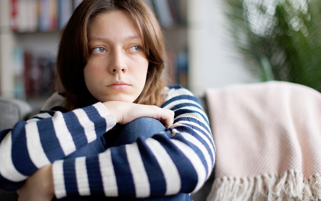 Foto einer jungen Frau, die depressiv auf dem Sofa sitzt