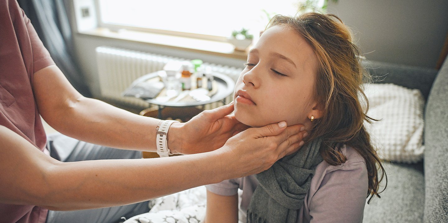 Eine Frau tatstet einem jungen Mädchen die Lymphknoten am Hals ab.