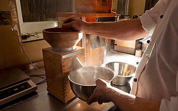 Klinikkantine Havelhöhe Foto eines Küchenangestellten, der eine Maschine bedient, die Bio-Getreide zu Haferflocken verarbeitet