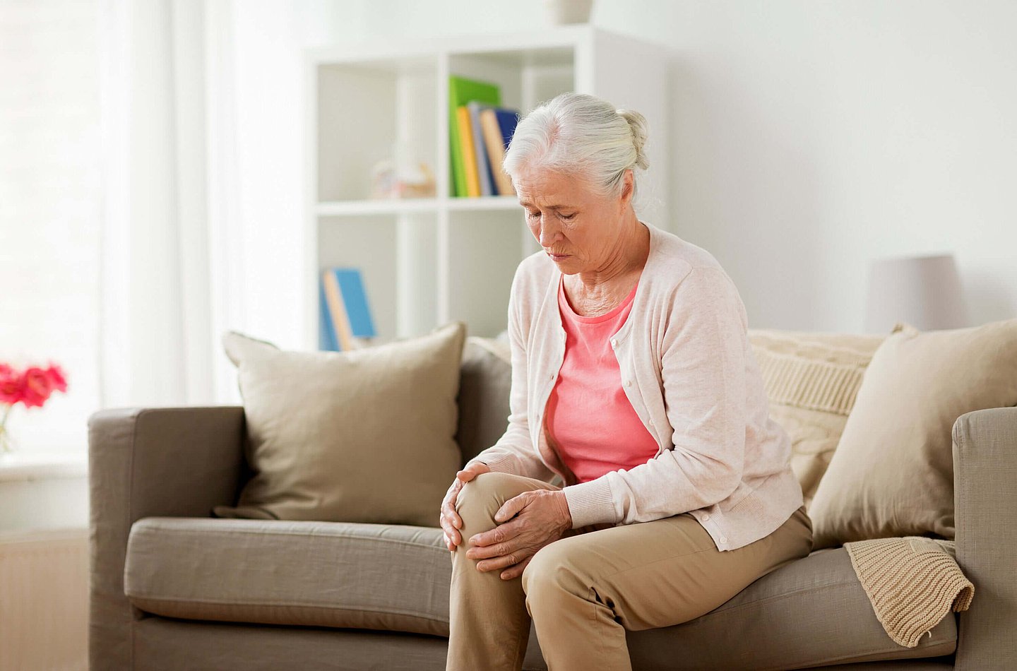 Eine ältere Frau hält sich das schmerzende Knie.