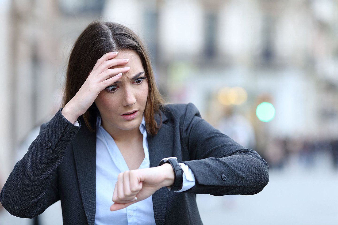 Frau schaut gestresst auf ihre Armbanduhr.