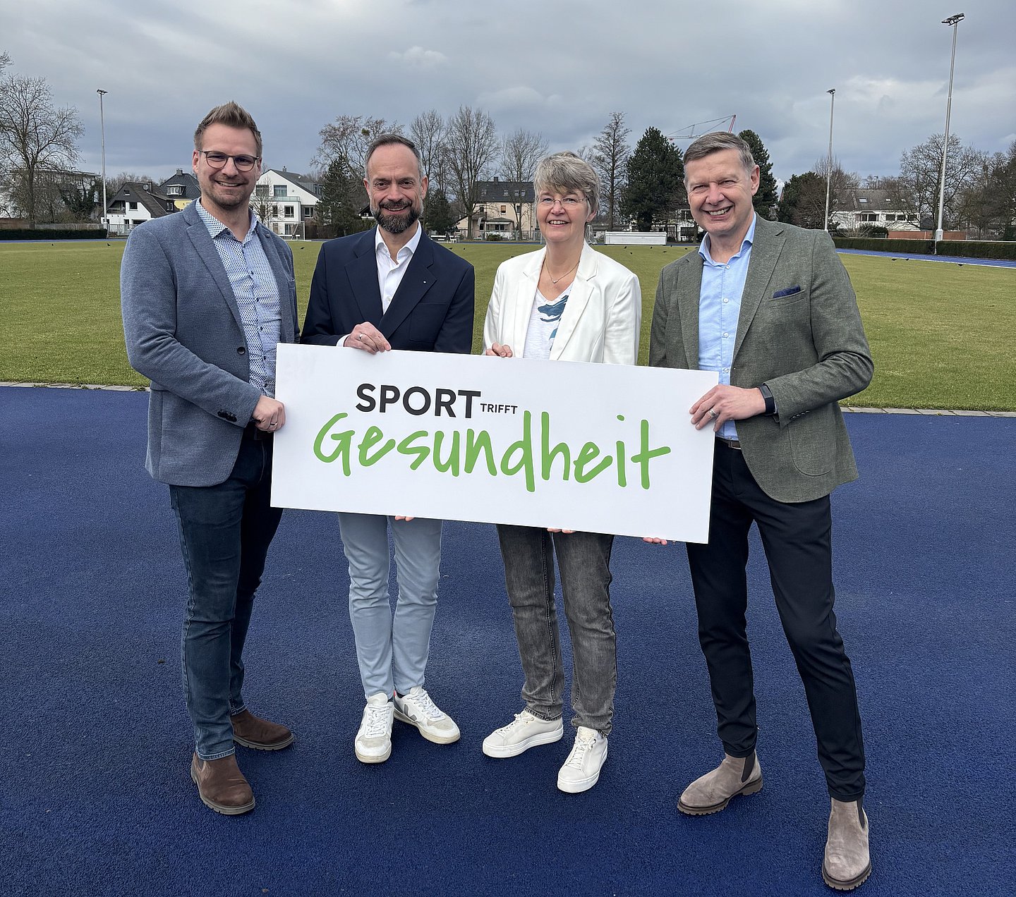 Maurice Hampel (FLVW), AOK-Chef Tom Ackermann, Marianne Finke-Holtz (FLVW) sowie Frank Simolka (AOK-Leiter Kunde und Markt) halten einen Banner mit der Aufschrift 'Sport trifft Gesundheit'.