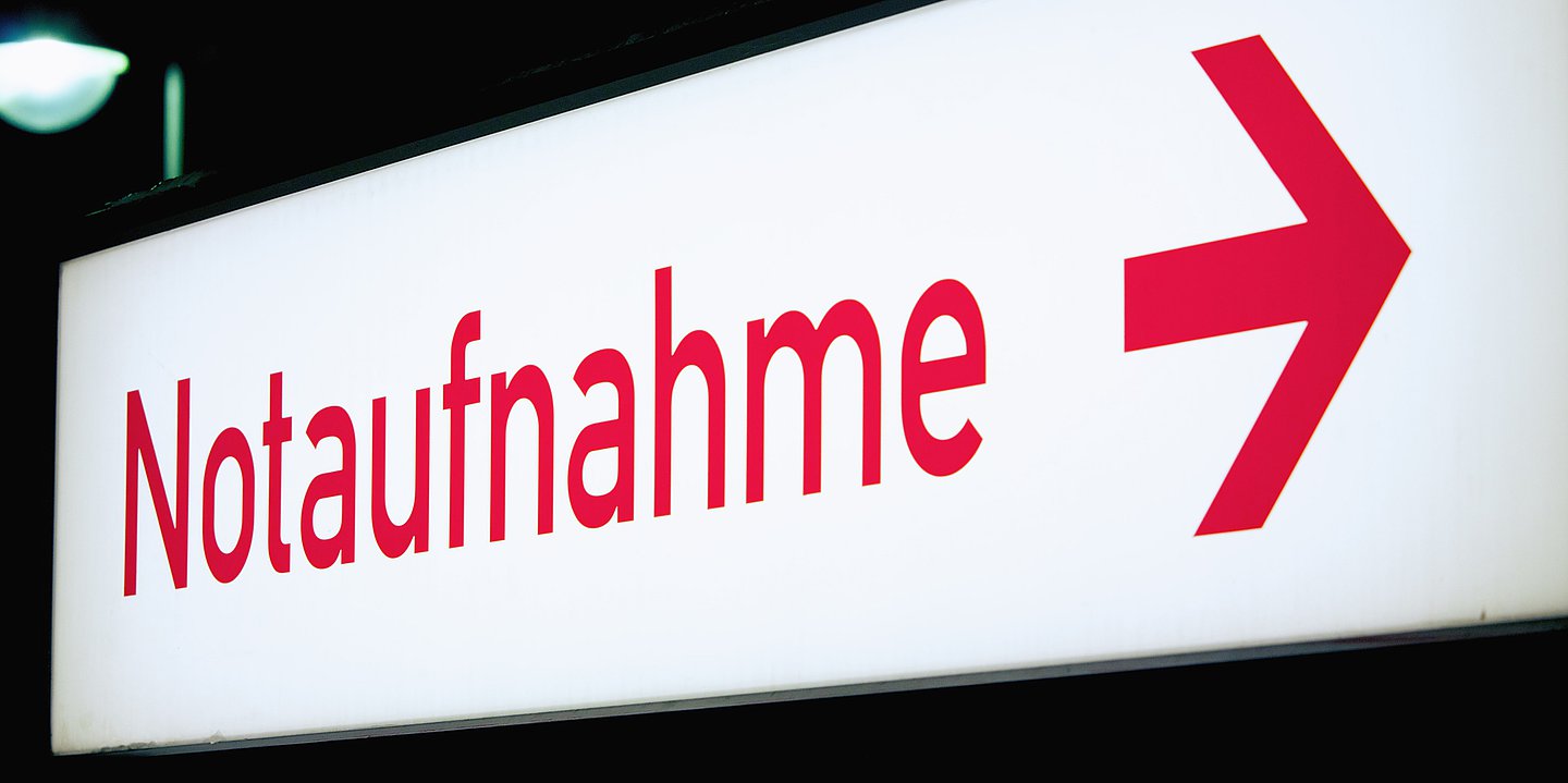 Foto: Weißes Leuchtschild mit roter Schrift "Notaufnahme" und Pfeil nach rechts.