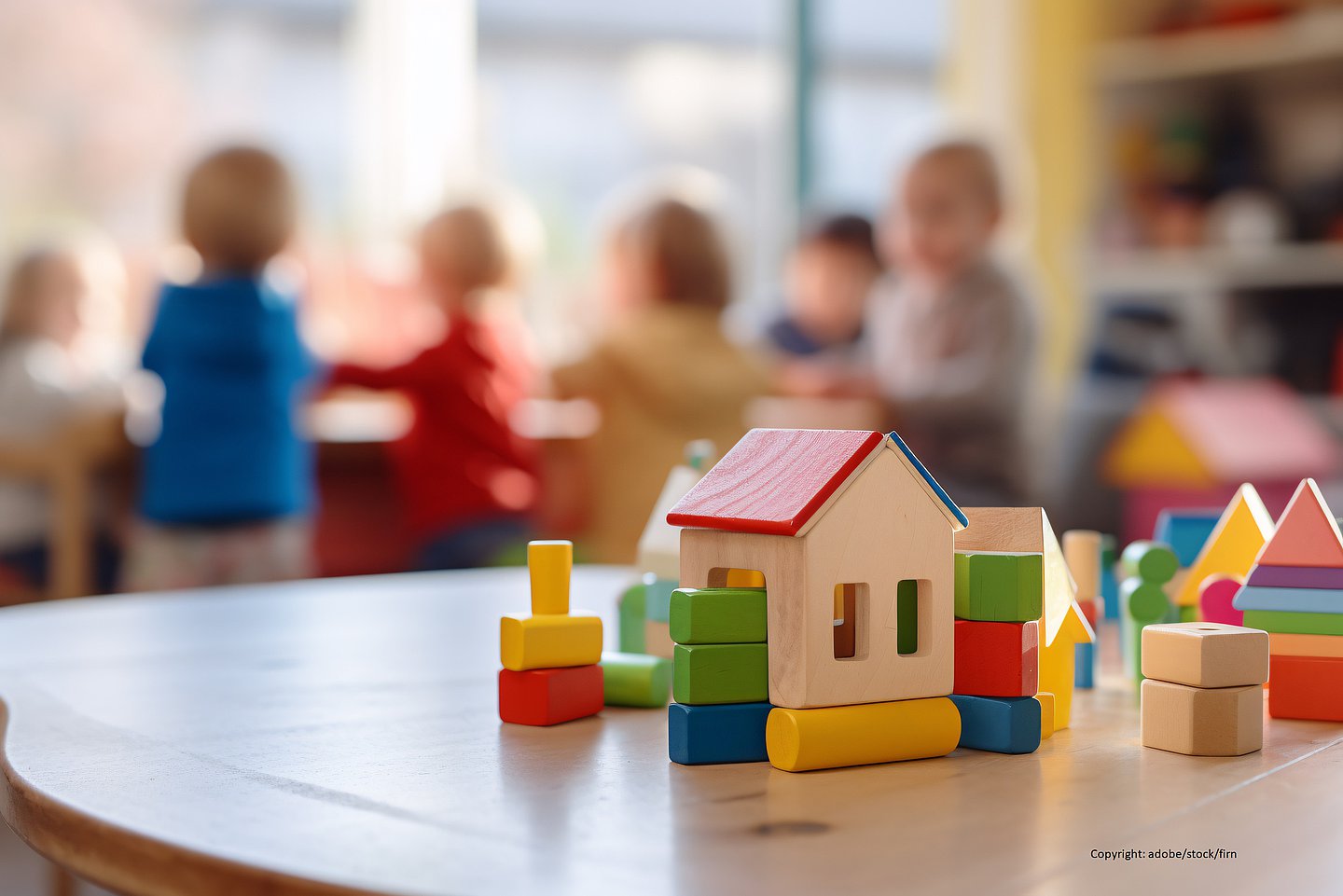 Kinder spielen in einer Kita. Im Vordergrund sind Bauklötze zu sehen.