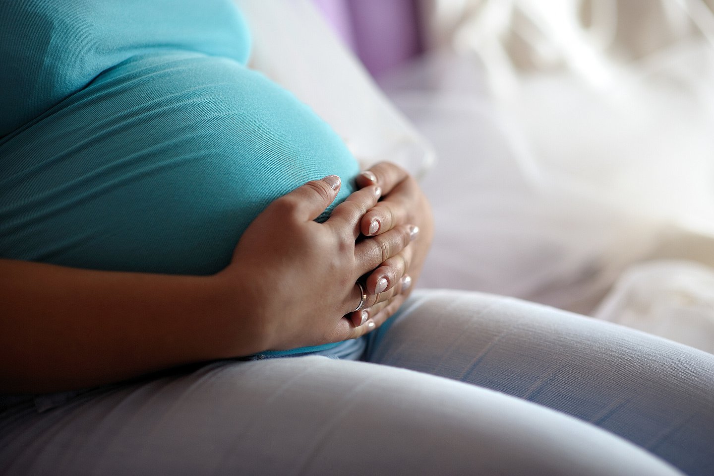 Eine schwangere Frau umfasst ihren Bauch.