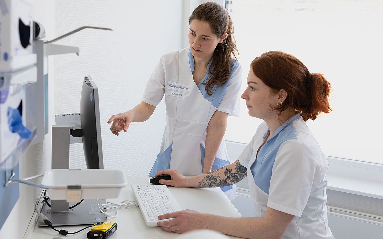 Foto: Arzthelferinnen gucken auf einen Computer