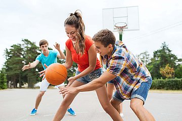 Jugendliche beim Streetbasketball Drei Jugendliche spielen Basketball.