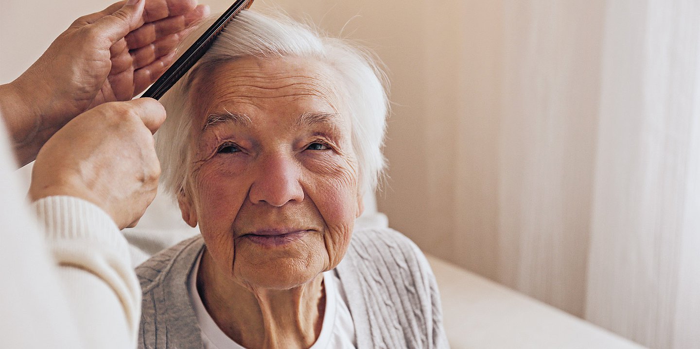Foto einer alten Damen, der die Haare gebürstet werden