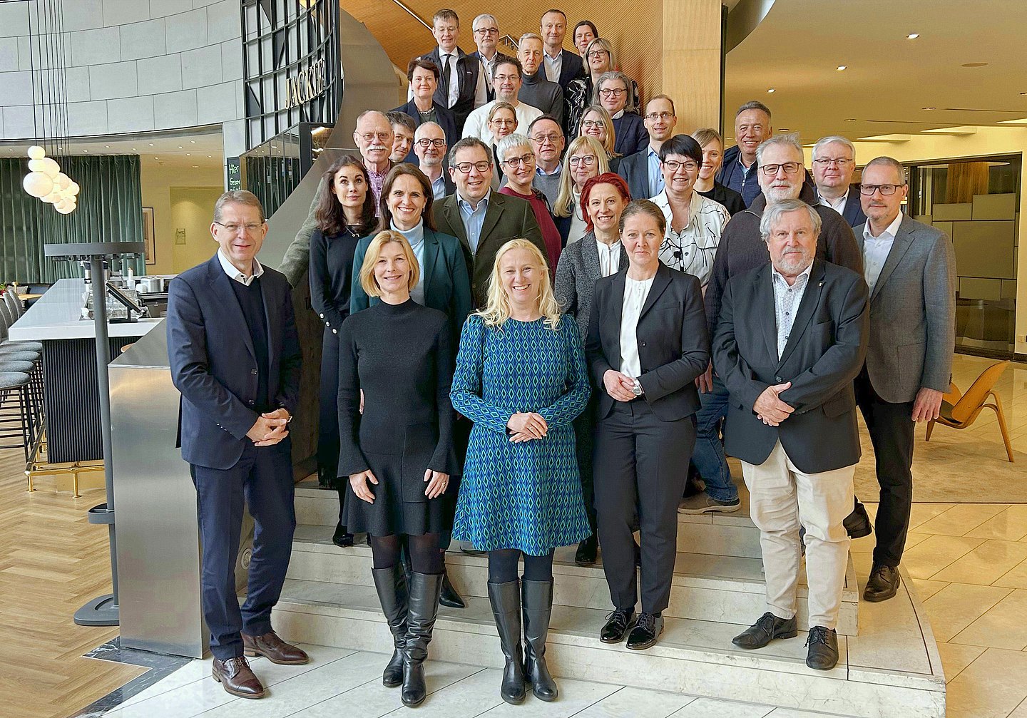 Das Gruppenfoto zeigt alle Beteiligten des Paktes für Gesundheit in Hessen auf einer Treppe in der Eingangashalle eines Bürogebäudes