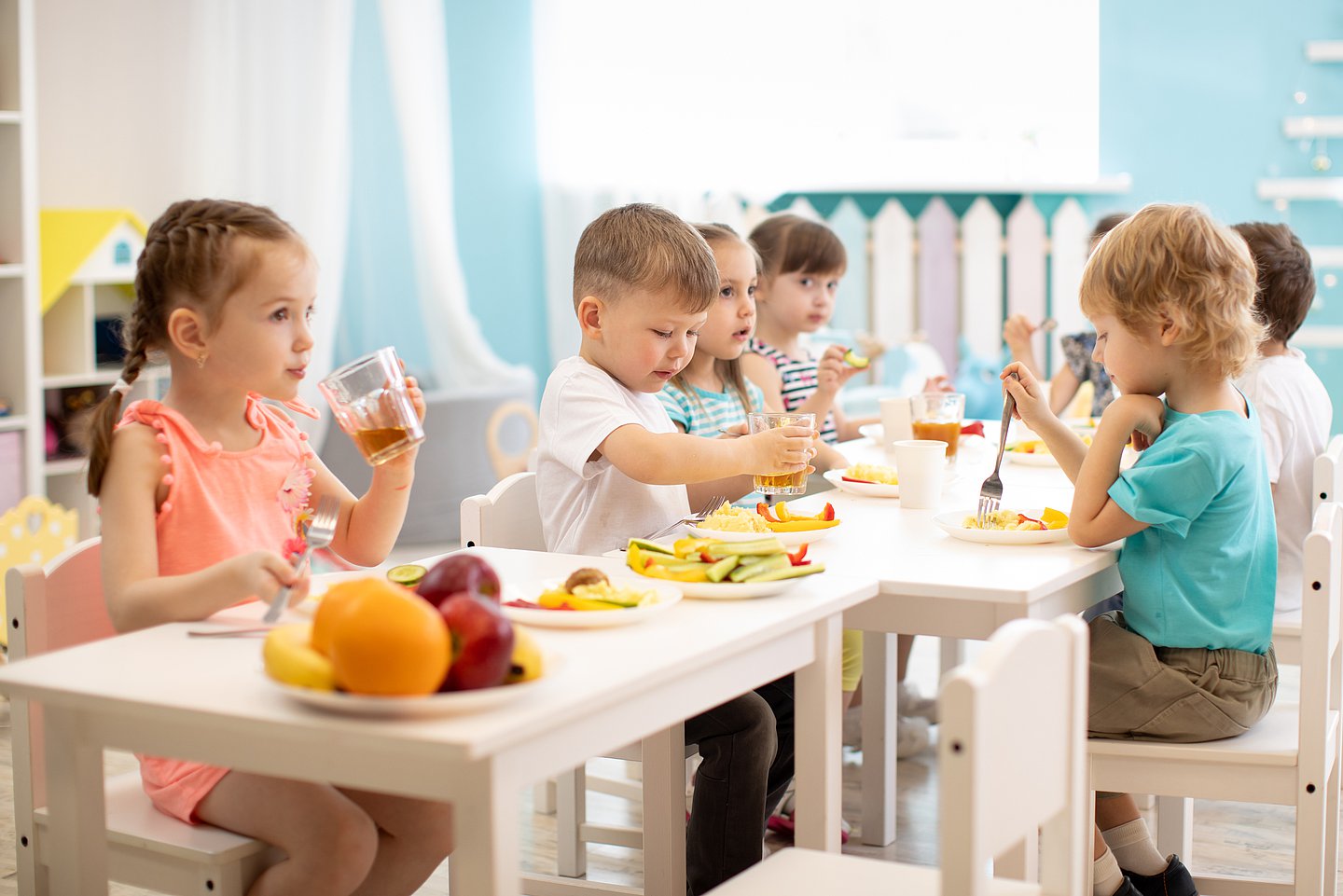 Kita-Kinder sitzen an einem Tisch und essen Obst