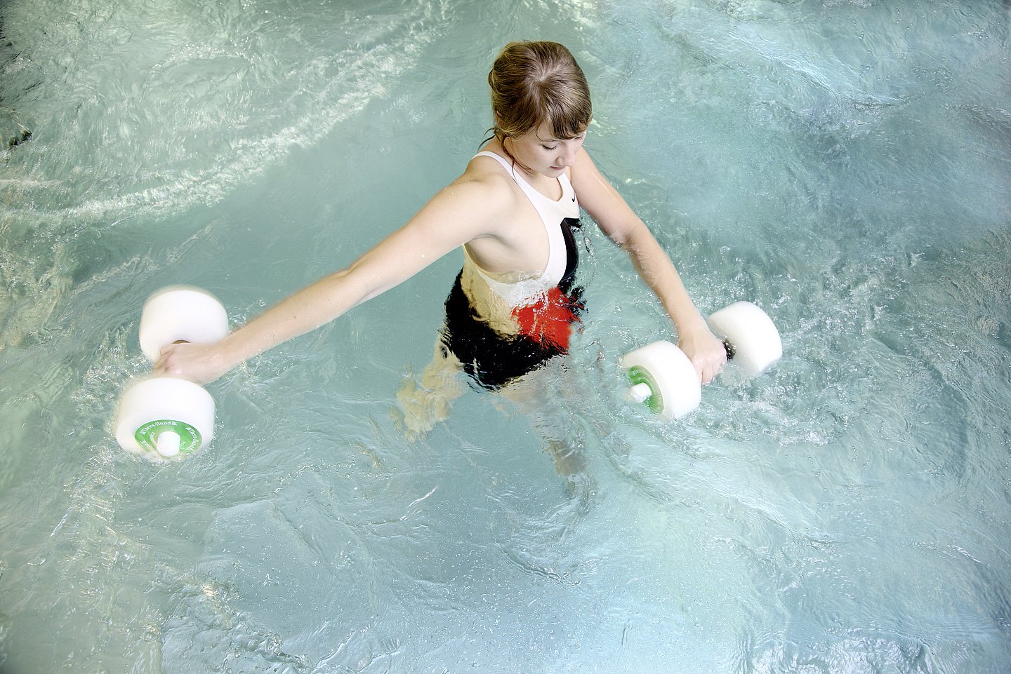 Foto: Eine junge Frau während der Physiotherapie im Wasser.