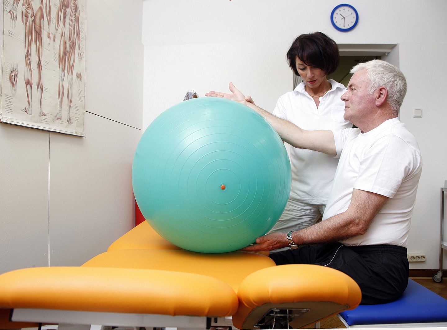 Foto: Eine Pflegekraft hilft einem älteren Patienten bei Übungen mit dem Gymnastikball.