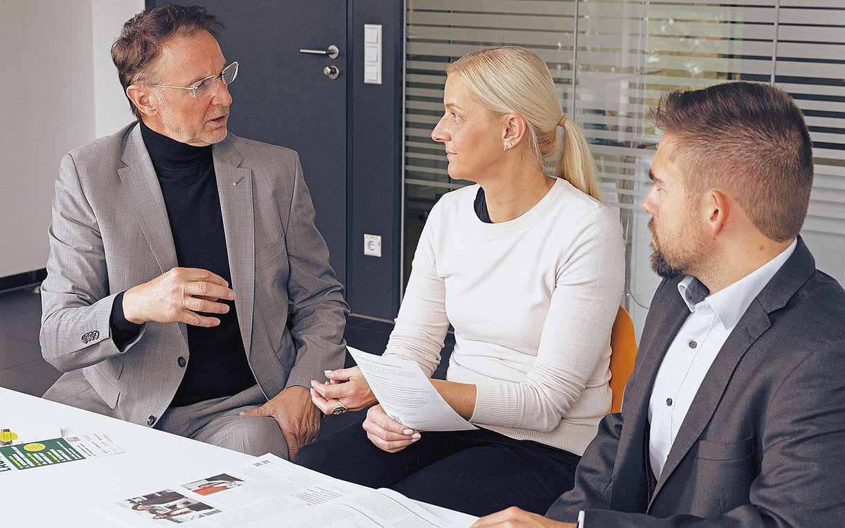 Drei Menschen sitzen nebeneinander und unterhalten sich