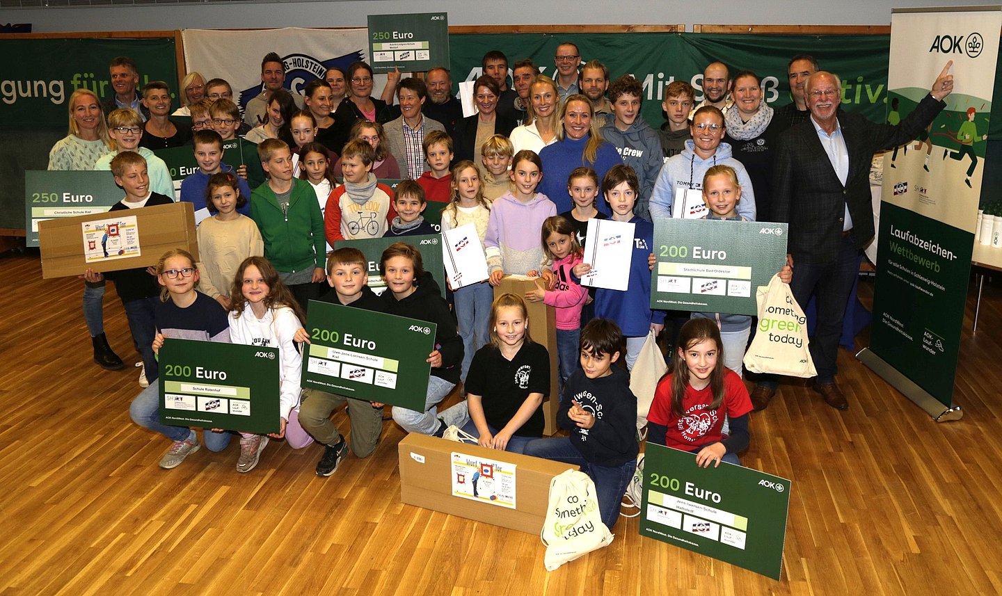 Die Kinder der 22 lauffreudigsten Gewinnerschulen halten strahlend ihre Gewinne und Urkunden in die Kamera.