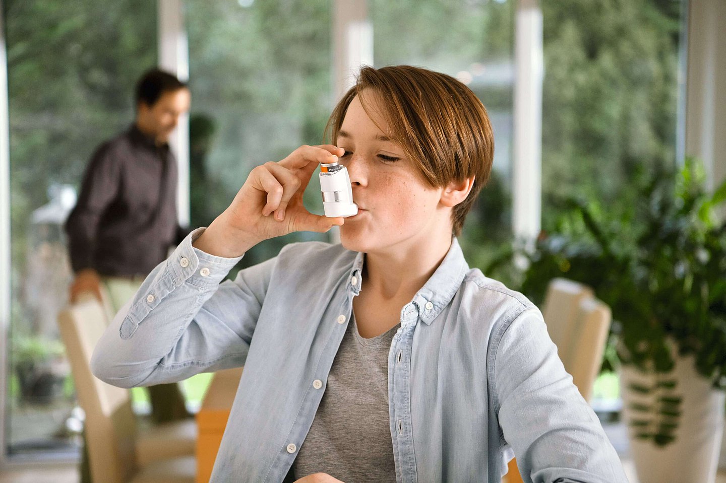 Eine Junge nimmt sein Asthma-Spray.