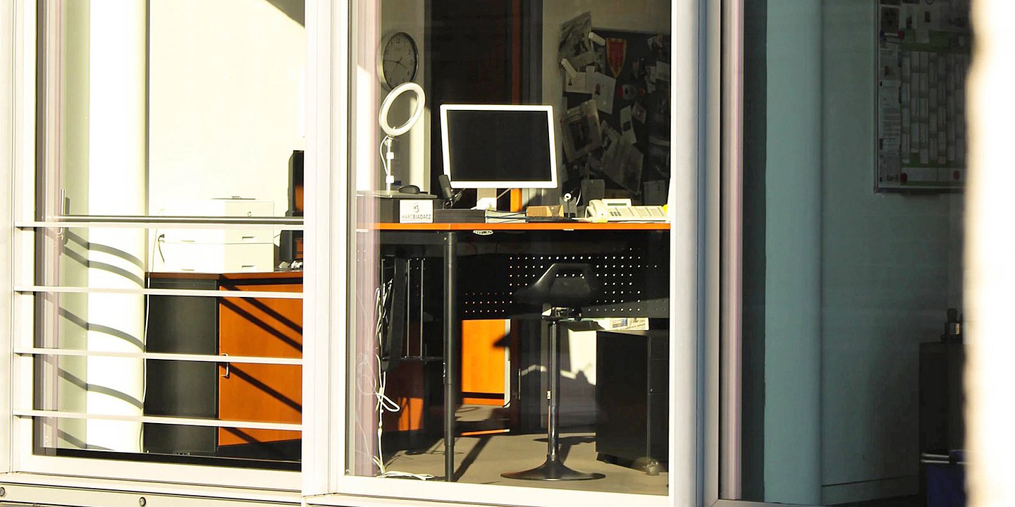 Foto von einem menschleeren Arbeitsplatz, von draußen durch das Fenster fotografiert